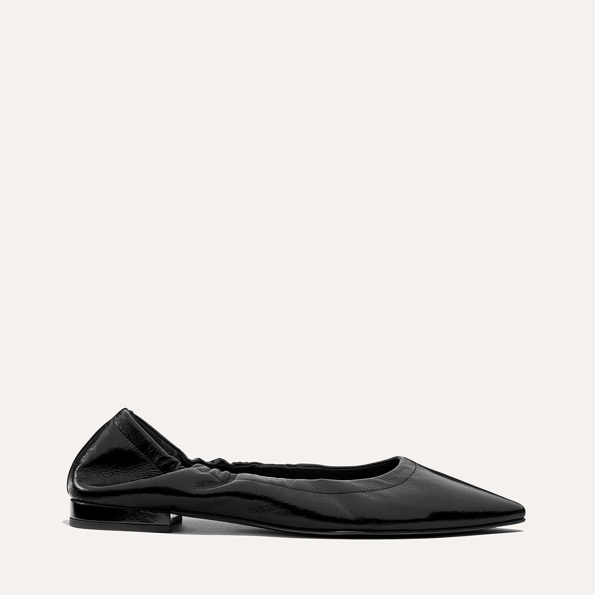 The Roma in Black Crinkle Patent by Margaux—a comfortable pointed-toe ballet flat with a low heel and gathered elastic at the heel—displayed on a light background.