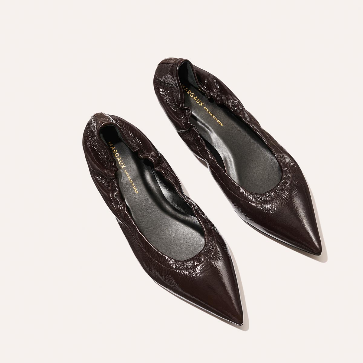 The Roma - Cocoa Crinkle Patent by Margaux are womens pointed-toe ballet flats in dark brown crinkle patent leather with ruched detailing, shown against a light background.