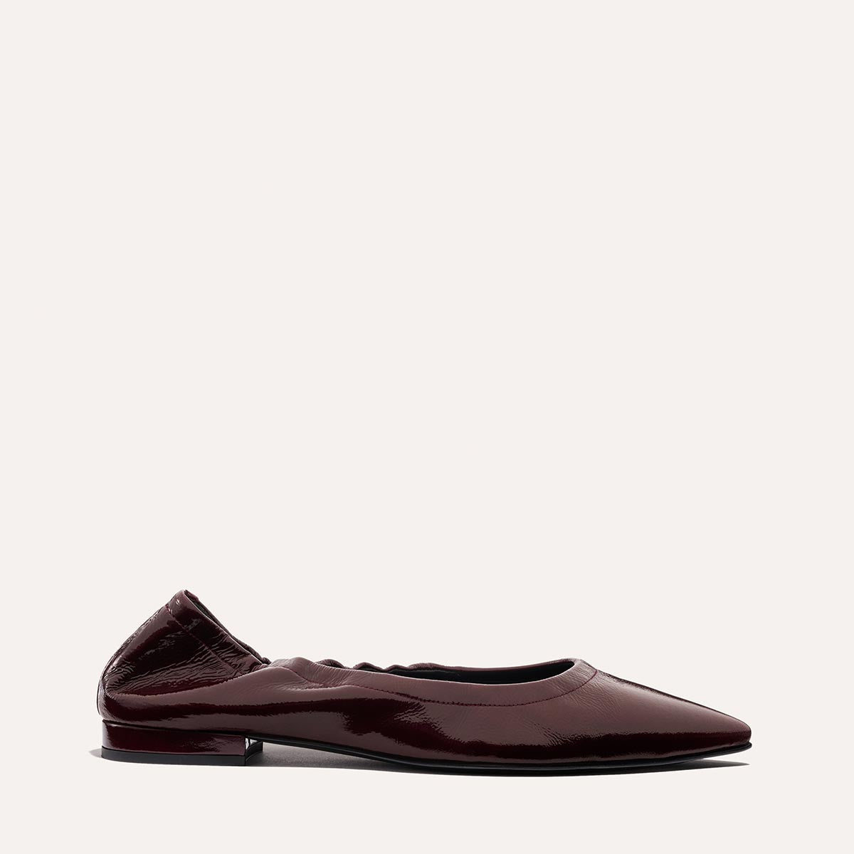 The Roma - Merlot Crinkle Patent by Margaux: a dark burgundy patent leather pointed-toe ballet flat with a low heel and gathered heel detail, showcased on a plain light background.