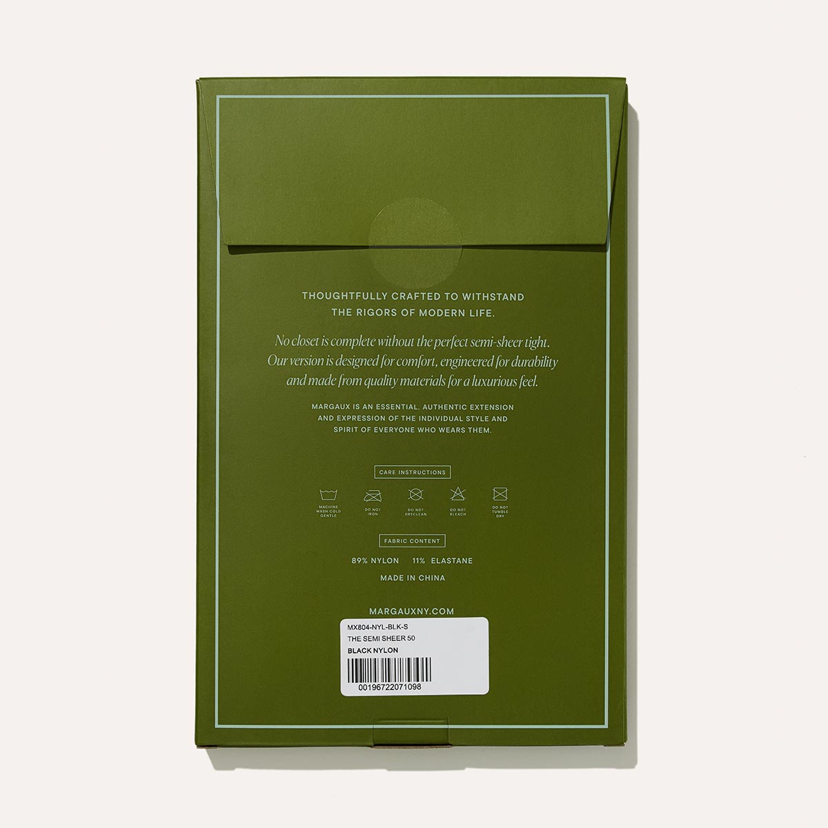 Olive green packaging with a flap and centered gold text showcases Margaux’s Semi-Sheer Tights - Black. A white barcode label with product info appears at the bottom, while a light beige background complements the Margaux boots collection.