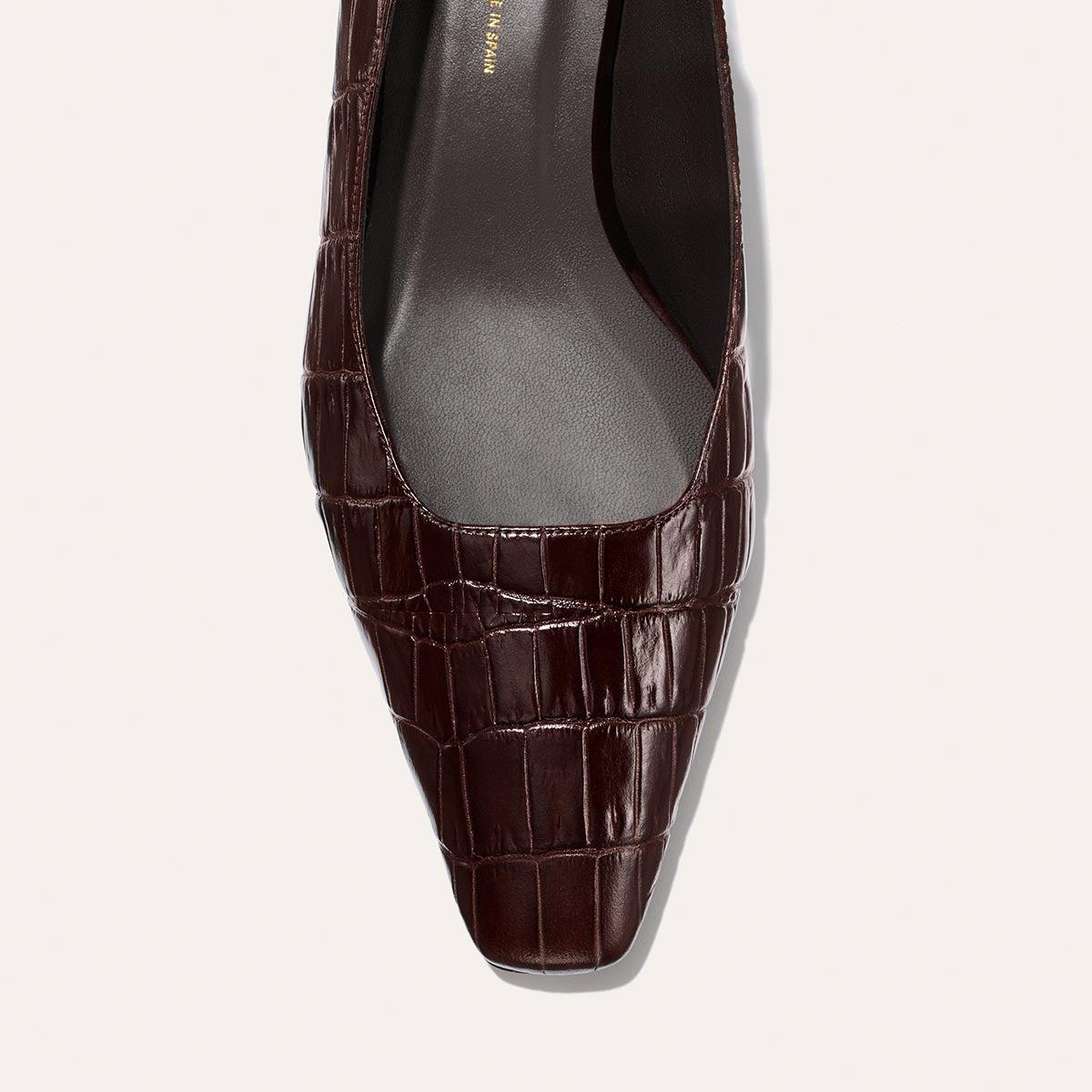 Close-up of Margaux’s The Sofia Sling in Espresso Croc Embossed— a dark brown, crocodile-embossed leather slingback flat with a squared toe and smooth black insole, photographed from above on a light background.