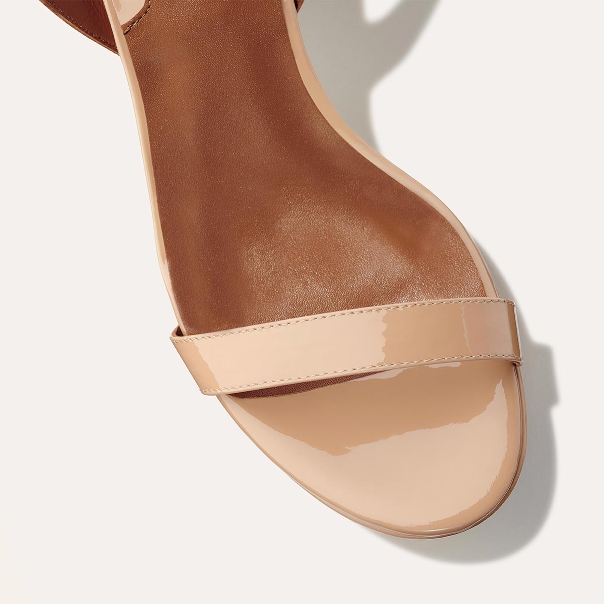 The Stella Platform in Dune Patent, featuring a sleek strap across the toes and a comfortable 3.5-inch block heel and platform.