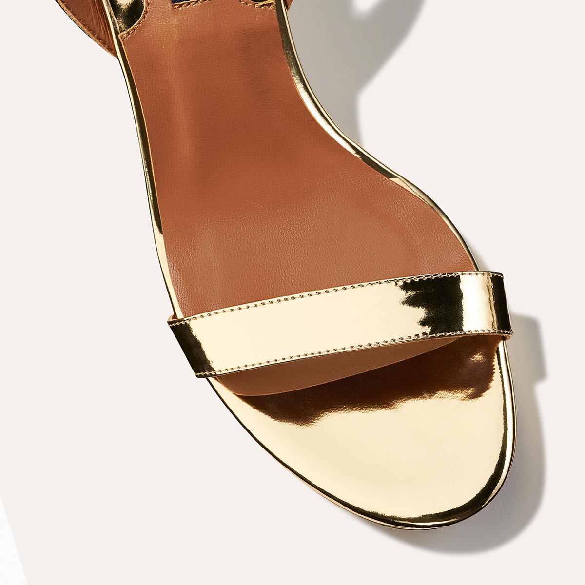 The Stella Platform in Gold Mirror, featuring a sleek strap across the toes and a comfortable 3.5-inch block heel and platform.