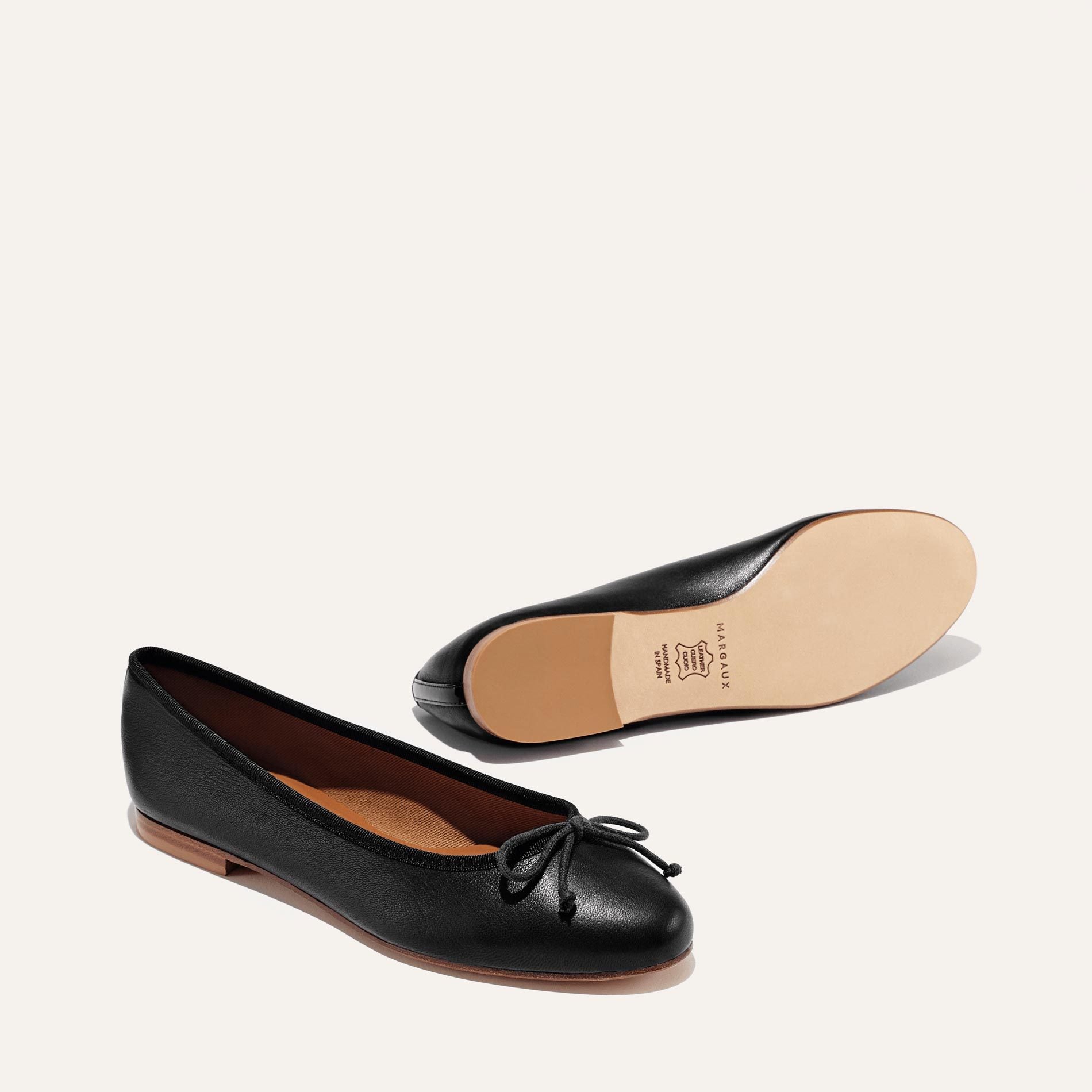 The Demi in Black Nappa, a comfortable ballet flat with a rounded toe and adjustable cord bow detail.