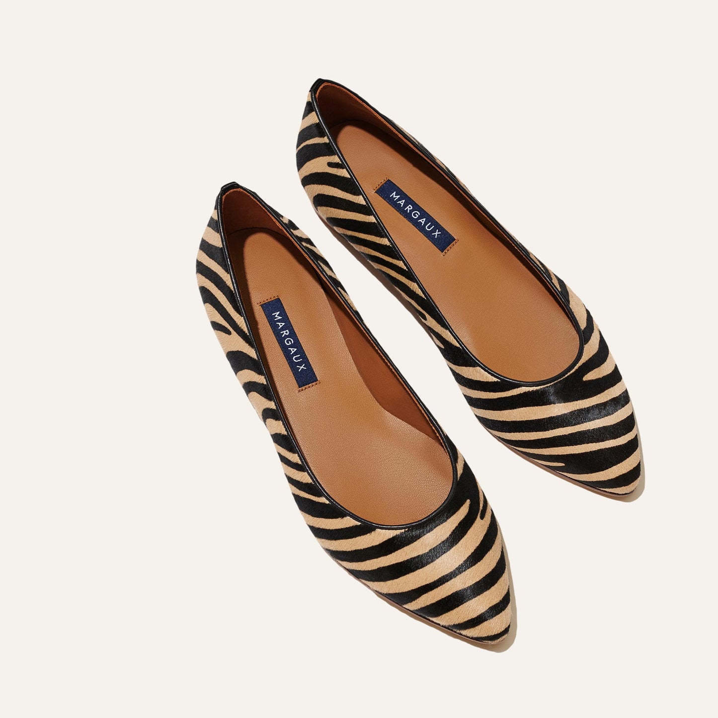 Margaux’s The Pointe - Zebra Haircalf is a pointed-toe flat in black and tan zebra print with sleek lines and tan insoles. As featured in Marie Claire, it delivers bold style with everyday comfort.