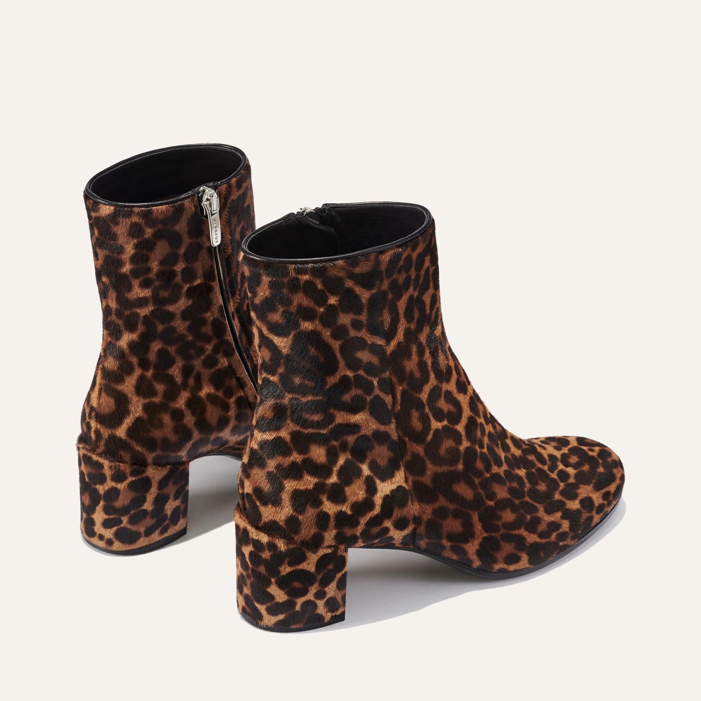 Margaux's The Boot - Chocolate Leopard Haircalf features elegant, ankle-high boots with chunky heels and an almond toe, showcasing a brown and black leopard print against a plain light background.