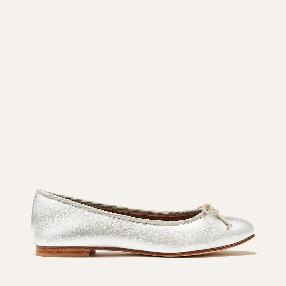 The Demi in metallic Silver Nappa, a comfortable ballet flat with a rounded toe and adjustable cord bow detail.