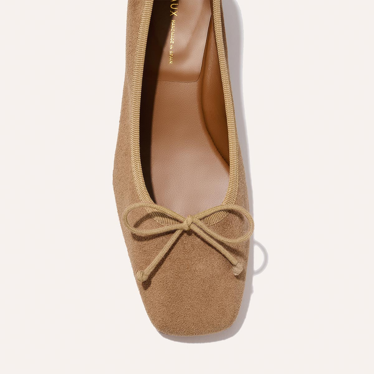 The Ada - Biscotti Suede by margaux-development is a tan suede ballet flat with sacchetto construction, a square toe, and a small front bow, shown in close-up against a light background.