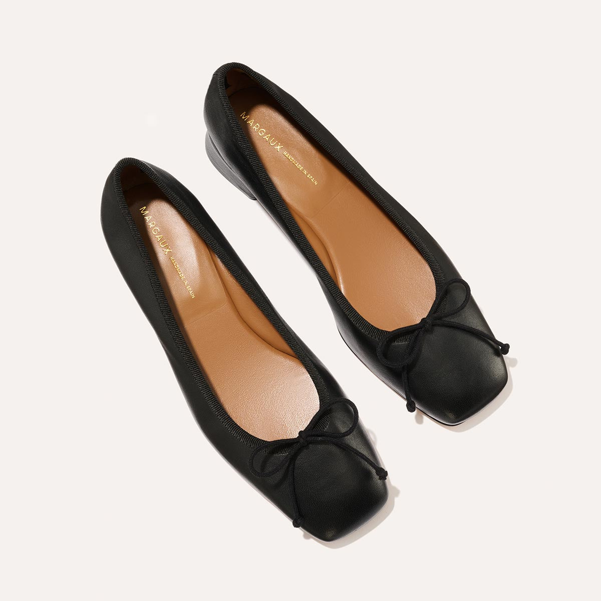 The Ada in Black Nappa, a comfortable ballet flat with a square toe, adjustable cord bow detail, and comfortable 1-inch block heel.