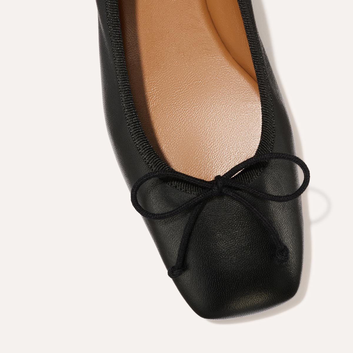 The Ada in Black Nappa, a comfortable ballet flat with a square toe, adjustable cord bow detail, and comfortable 1-inch block heel.