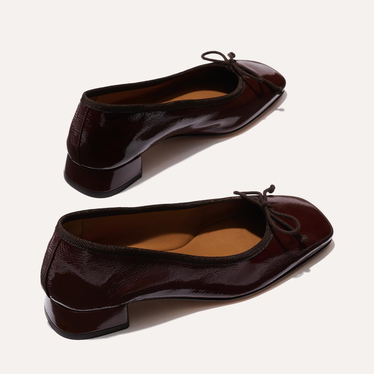 The Ada in Espresso Crinkle Patent, a comfortable ballet flat with a square toe, adjustable cord bow detail, and comfortable 1-inch block heel.