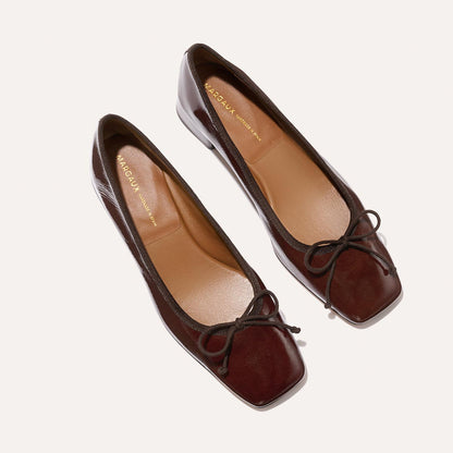 The Ada - Espresso Crinkle Patent by Margaux: brown patent leather ballet flats with square toes, brown trim, and matching bow detail, crafted with sacchetto construction and shown from above on a light background.
