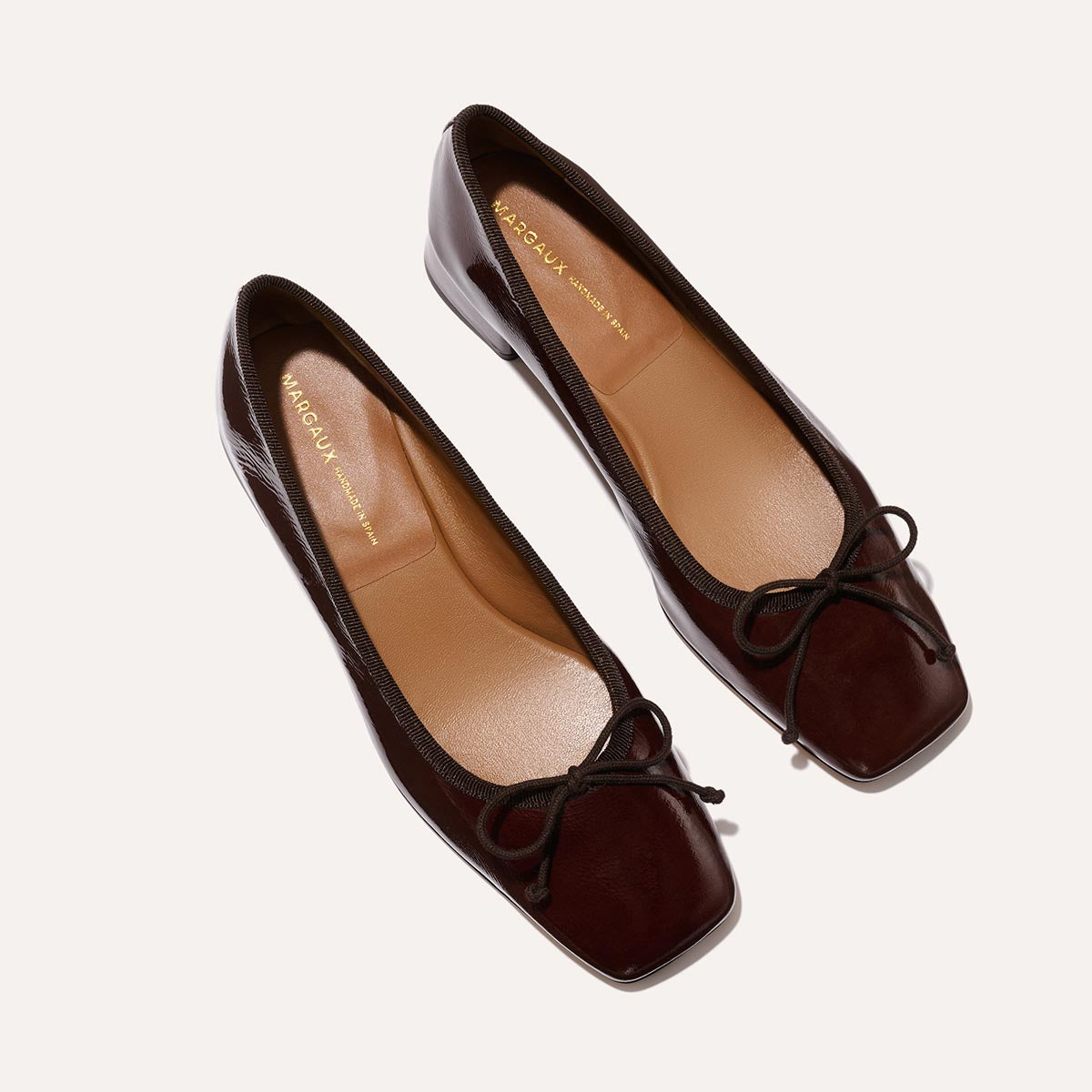 The Ada in Espresso Crinkle Patent, a comfortable ballet flat with a square toe, adjustable cord bow detail, and comfortable 1-inch block heel.