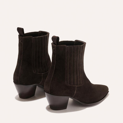 The Agnes Boot by margaux-development in Cocoa Suede features low stacked heels, elastic side panels, squared-off welt, and pull tabs—Western-inspired ankle boots shown on a light background.