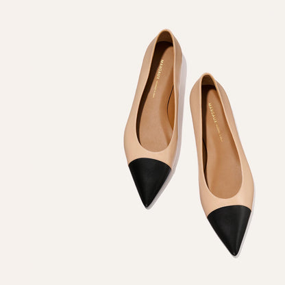 The Alba - Dune and Black Nappa ballet flats by Margaux, with pointed toes and black caps, are placed side by side on a light neutral background.