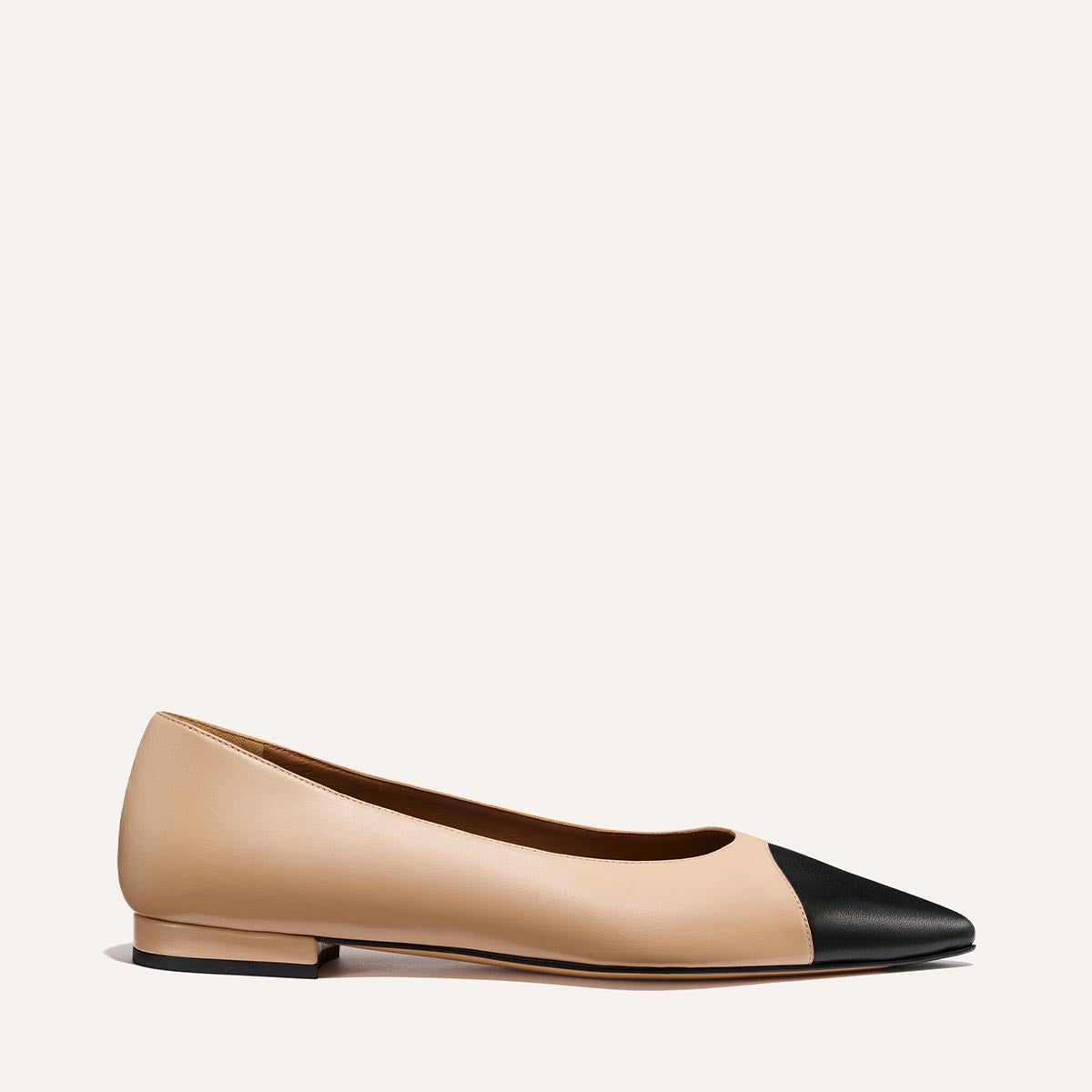 The Alba by Margaux is a tan and black Nappa leather ballet flat with a low heel, pointed toe, padded insole, and black cap toe, shown from the side on a plain white background.