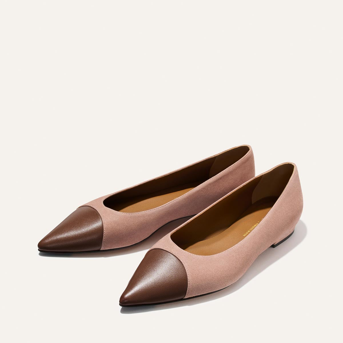 Pair of pink and brown pointed-toe flats on a white background
