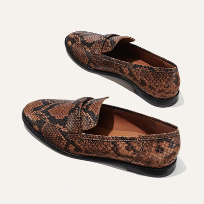 The Andie Loafer - Espresso Python Embossed by Margaux features a snakeskin pattern and black soles. Displayed on a light background, both top and side views highlight their stylish design—ideal for work.