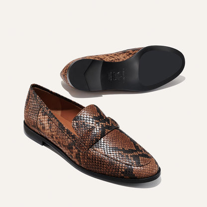 The Andie Loafer - Espresso Python Embossed by Margaux features a brown and black snakeskin pattern, shown from the side and bottom to highlight its flat black sole—making it a stylish work shoe choice.