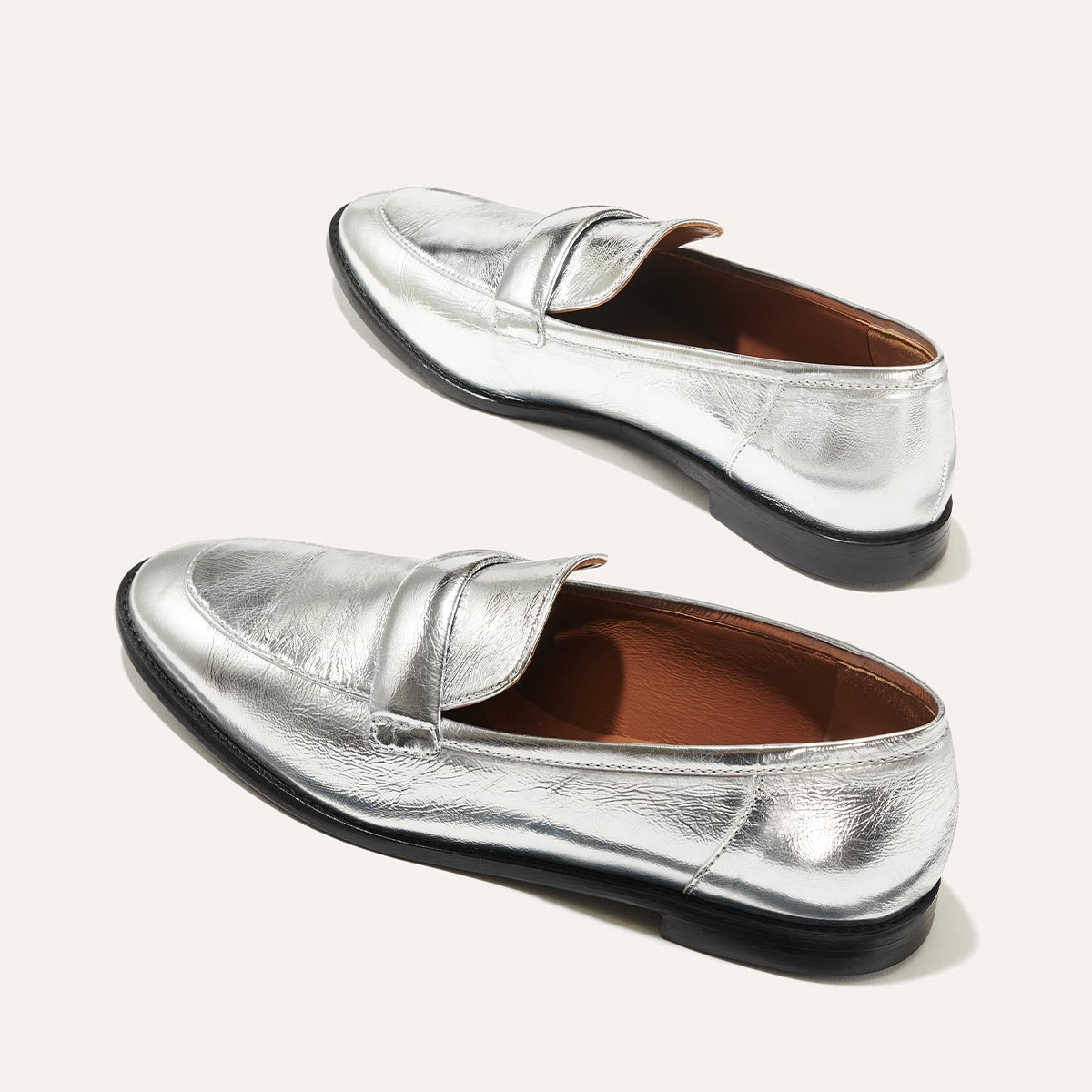 The Andie Loafer in shiny Silver Crinkle Mirror, featuring a sleek structured design made from smooth Italian nappa leather with a minimalistic padded keeper detail.