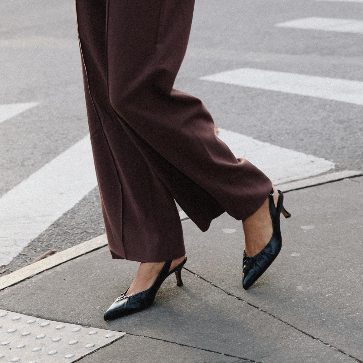 The Anya Slingback in shiny Black Crinkle-Gloss Nappa, featuring a ruched tapered toe with an adjustable buckle and a comfortable 2.5-inch black heel.