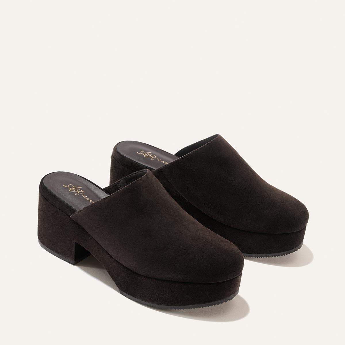 A pair of Margaux Alison Roman x Margaux: The Atlantic Clog in dark chocolate suede, featuring chunky high heels and closed toes, displayed on a plain light background.