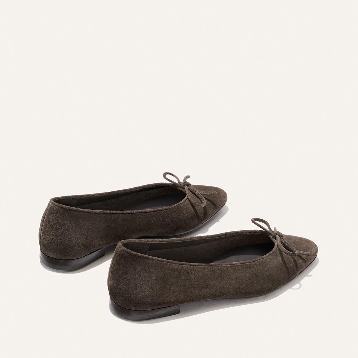 A pair of Alison Roman x Margaux: The Salamanca - English Brown Suede ballet flats with small bows on the toes, displayed against a plain white background.