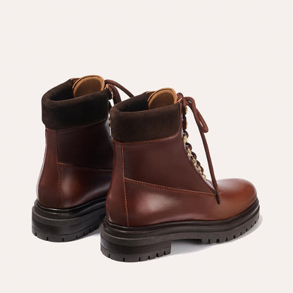 The Aspen Boot - Russet Calf by margaux-development: brown leather lace-up boots with thick black soles and dark brown suede collars, shown from the back and side on a light background.
