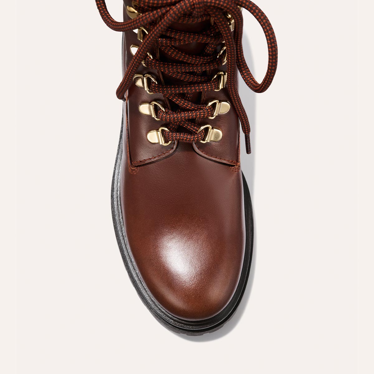 Top view of The Aspen Boot - Russet Calf by margaux-development: brown leather with dark brown laces in gold eyelets, smooth rounded toe cap, and black sole, set against a light background.