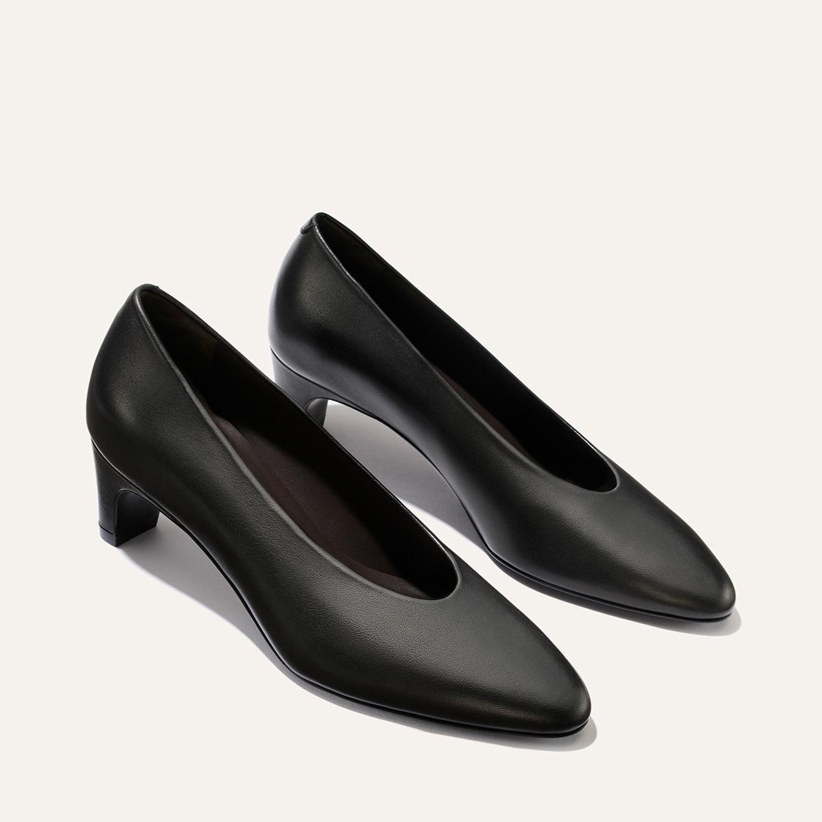 A pair of The Augusta Glove Pump in black nappa leather by Margaux, featuring classic pointed toes and low heels, displayed on a plain light background.