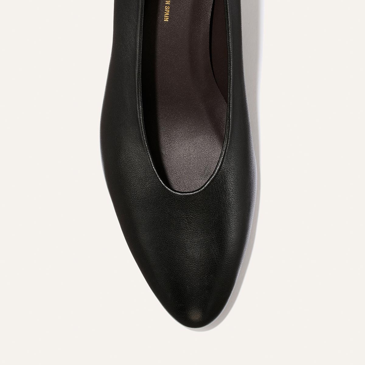 A close-up top view of The Augusta Glove Pump in Black Nappa by Margaux, featuring a pointed toe, on a light background.