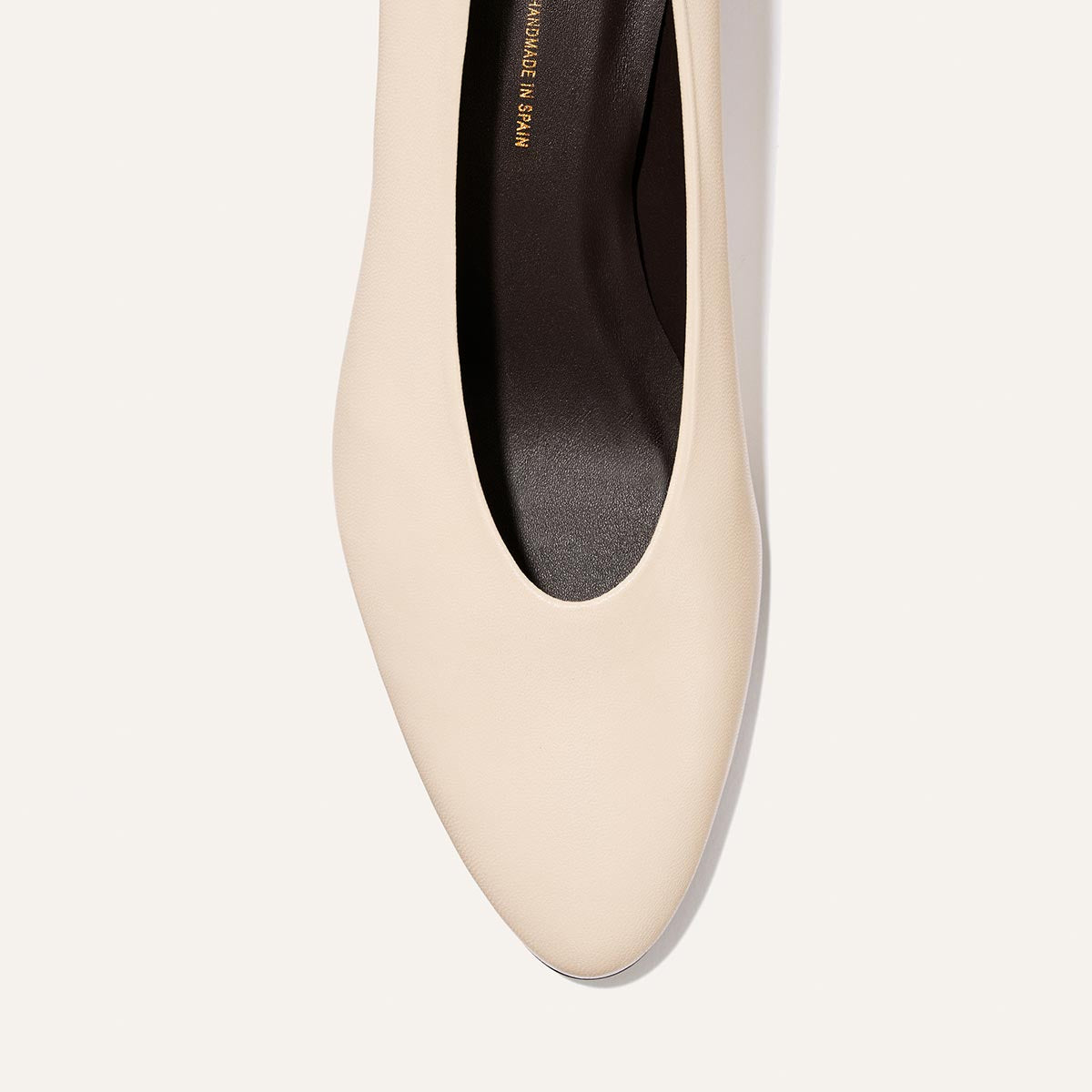 The Augusta Glove Pump in Bone Nappa by Margaux, a beige pointed-toe flat with a black interior, is shown from above against a plain light background.
