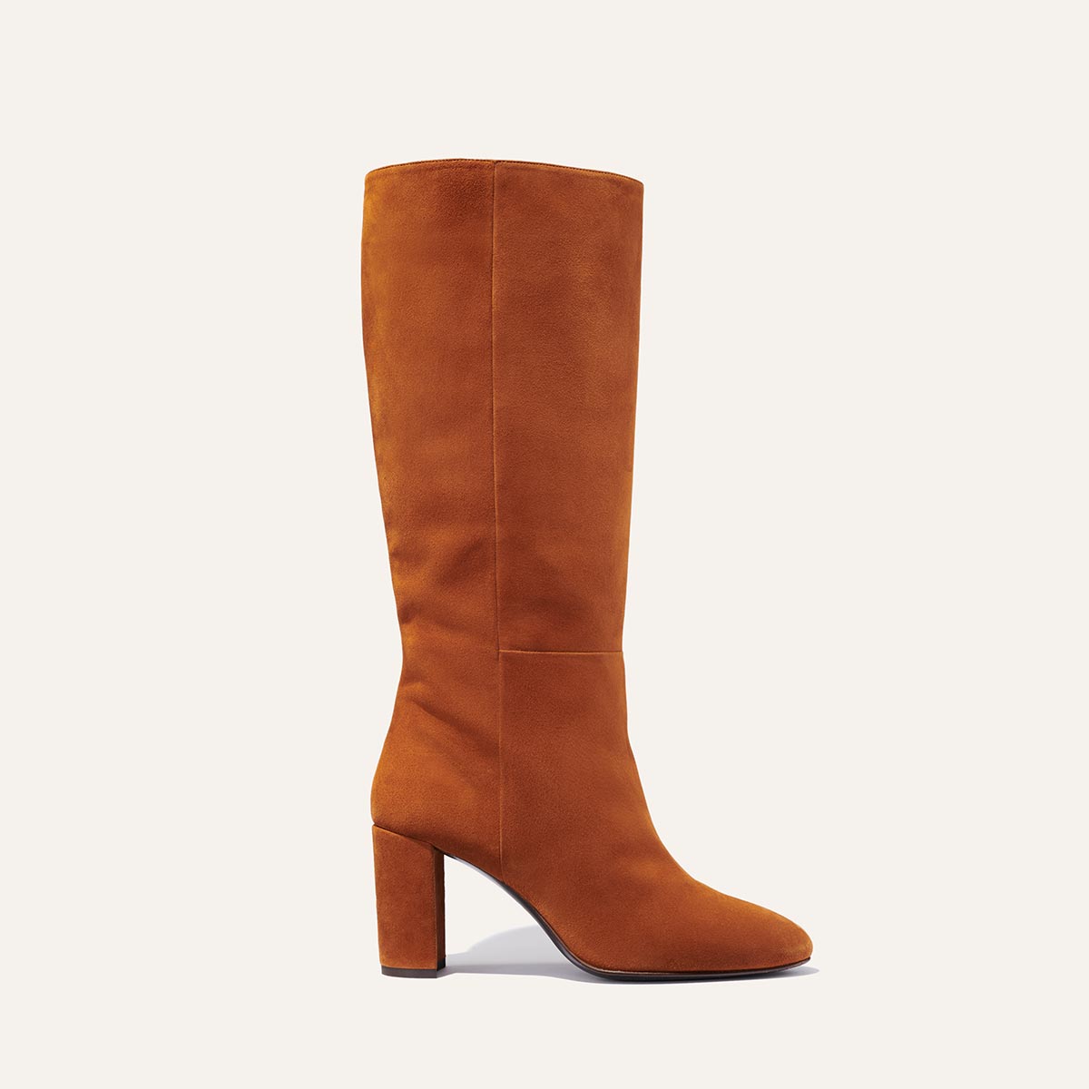 Margaux's knee-high Bleecker Boot in soft, tawny brown Italian suede with walkable heel and almond-shaped toe
