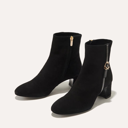 The Bowery Boot in Black Suede, crafted from luxurious Italian suede featuring a sleek almond toe, elegant breasted heel, and a gold-tone buckle detail. 