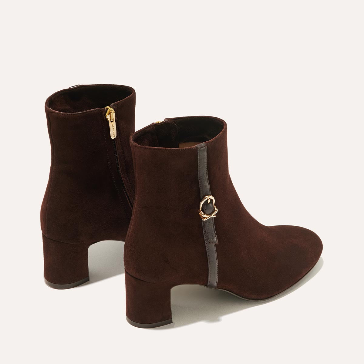 The Bowery Boot in Chocolate Suede, crafted from luxurious Italian suede featuring a sleek almond toe, elegant breasted heel, and a gold-tone buckle detail. 