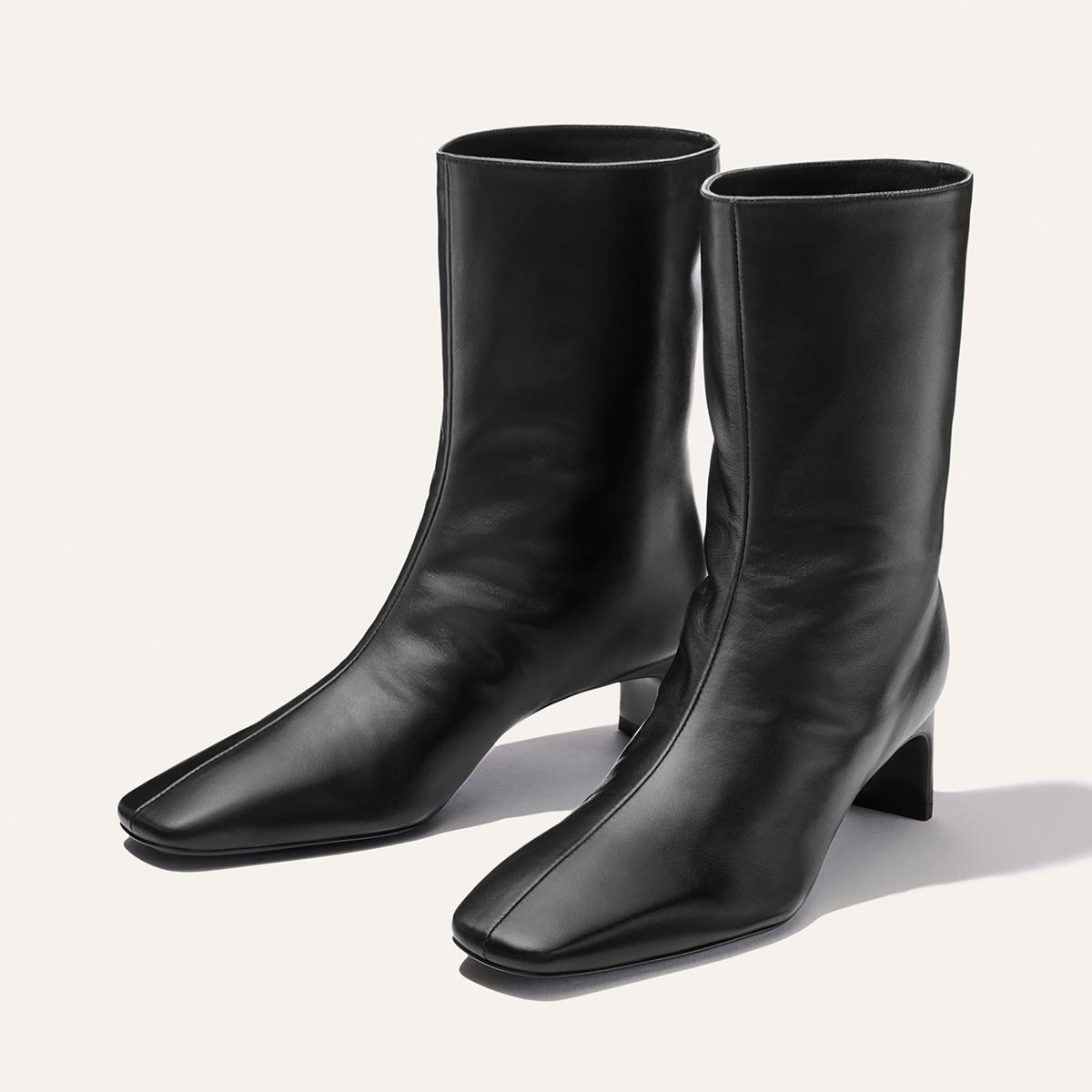 A pair of Margaux’s The Brera Boot in black nappa leather, featuring square toes and mid-height block heels, displayed on a plain light background.