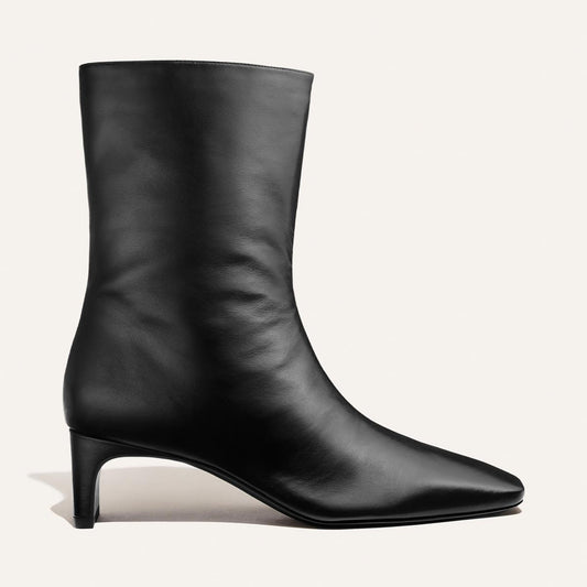 Introducing The Brera Boot - Black Nappa by Margaux: an elegant black leather ankle boot featuring a low heel and pointed toe, displayed against a minimalist white background.