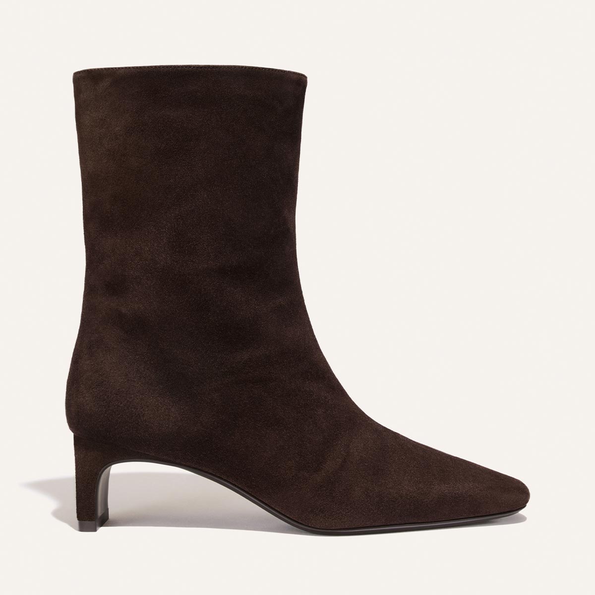 The Brera Boot in Molasses Suede by Margaux—a dark brown suede mid-calf boot featuring a pointed toe and low heel—is displayed on a plain light background.