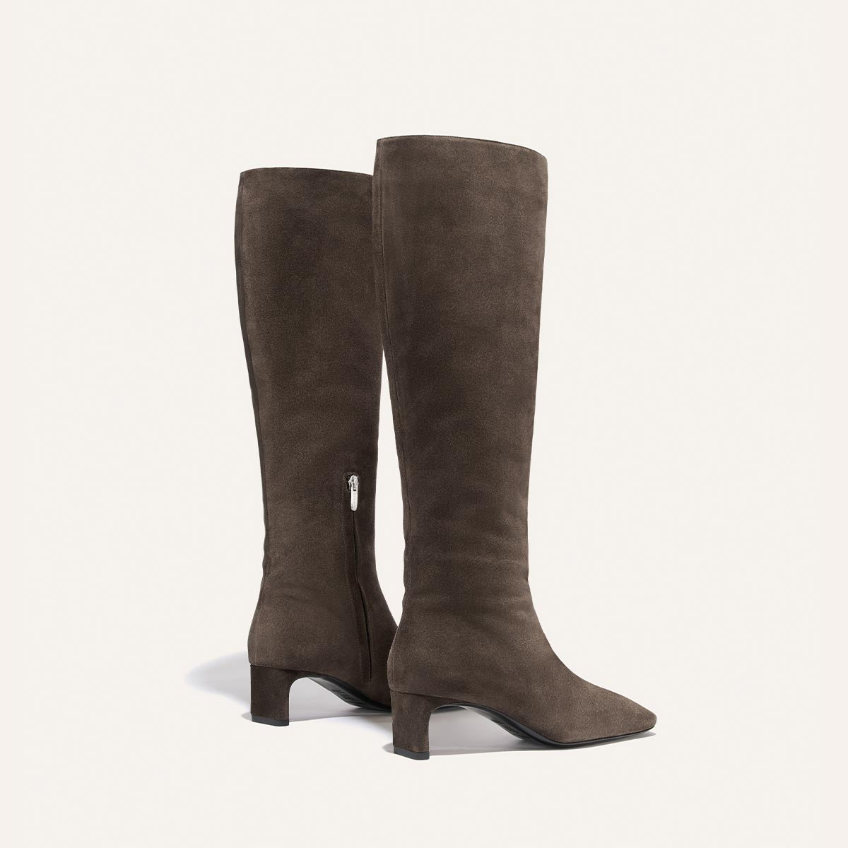 The Brera Knee-High Boot by Margaux, crafted in English Brown Suede, features a low, walkable block heel, an inner side zipper, and a padded insole for extra comfort, beautifully displayed against a plain light background.