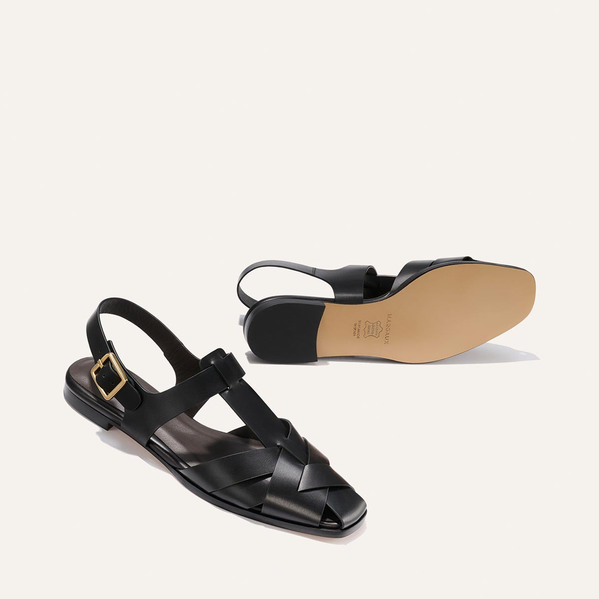 Black sandal with a gold buckle on a white background