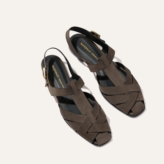 Margaux’s The Calypso Fisherman - English Brown Suede sandals feature a dark brown suede interwoven pattern with ankle straps and gold buckles.
