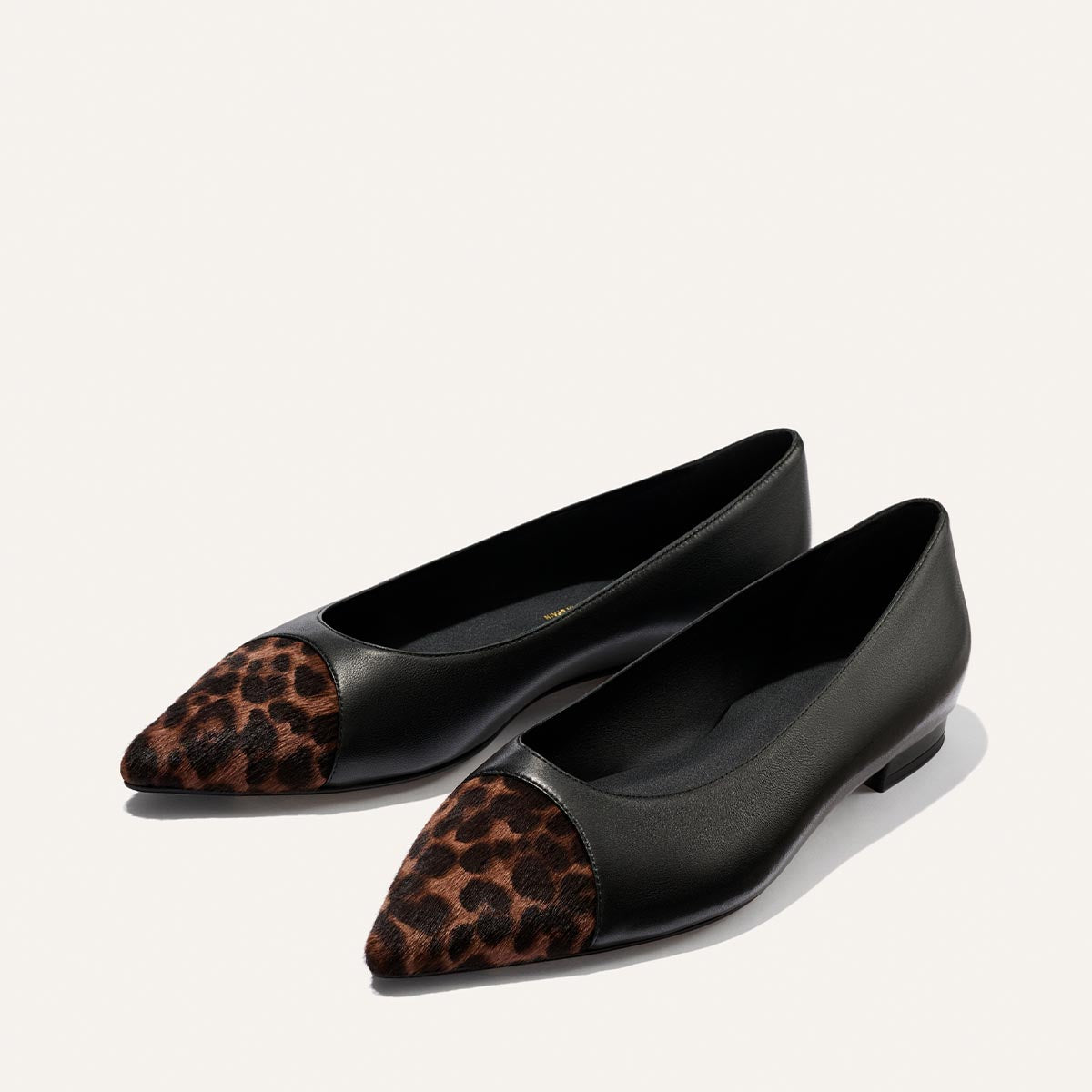 The Alba - Black Nappa and Leopard Haircalf flats by Margaux feature black pointed toes with leopard haircalf detailing on the caps and a comfortable padded insole, presented against a simple light background.