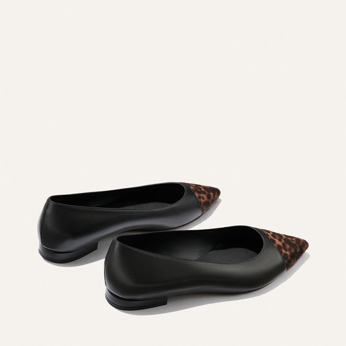 A pair of Margaux's "The Alba" flats in Black Nappa and Leopard Haircalf, featuring a pointed toe with leopard print detail and a comfortable padded insole, displayed on a light background.