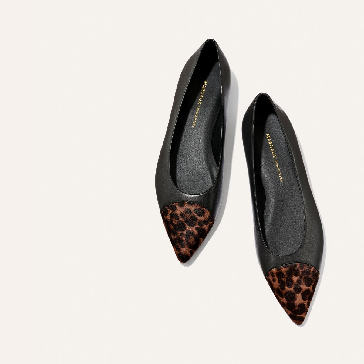 A pair of Margaux "The Alba" flats in black nappa with leopard haircalf detail on the pointed toe and a comfortable padded insole, displayed on a light background.
