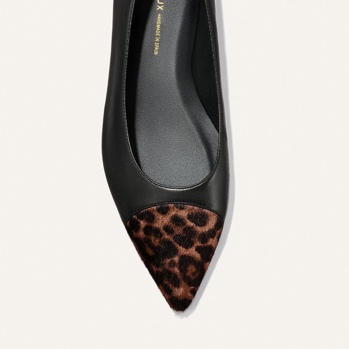 The Alba by Margaux is a black nappa pointed-toe ballet flat with a brown and black leopard haircalf tip, featuring a comfortable padded insole, shown from above on a white background.