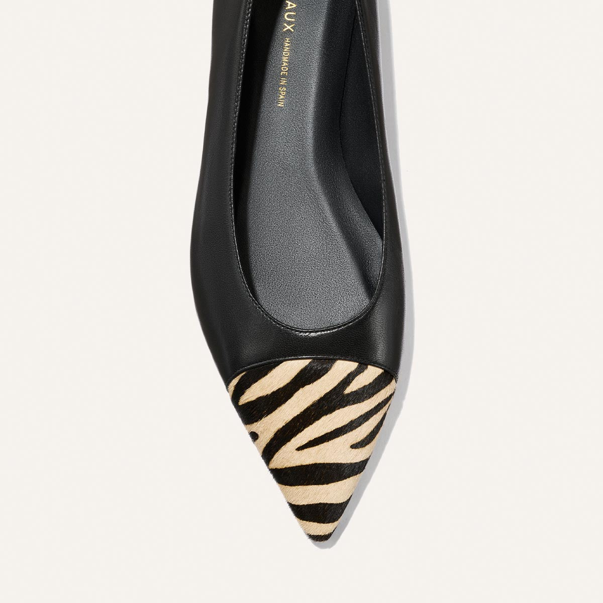 The Alba by Margaux is a black nappa ballet flat featuring a pointed toe, zebra haircalf print on the toe cap, and a comfortable padded insole—shown from above against a white background.