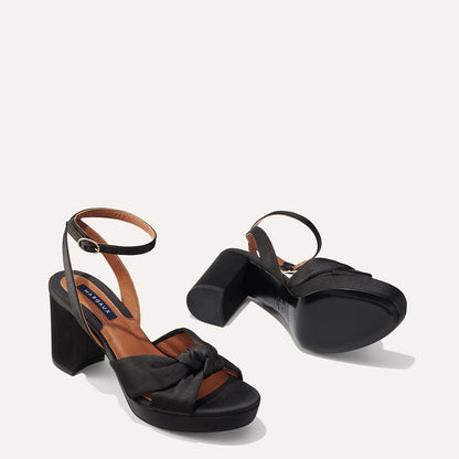 The Carmine Platform in Black Satin featuring a plush knot detail, a comfortable 1-inch platform, and a 3.5-inch block heel.