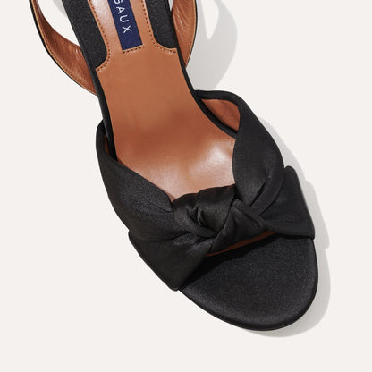 The Carmine Platform in Black Satin featuring a plush knot detail, a comfortable 1-inch platform, and a 3.5-inch block heel.