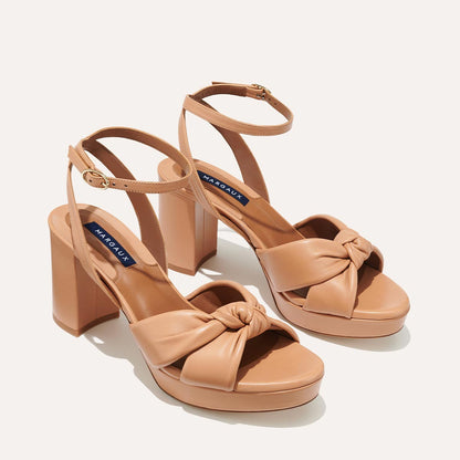The Carmine Platform - Desert Nappa by margaux-development features tan block heels, ankle straps, and a plush knot front design for a comfortable fit, shown on a light background.