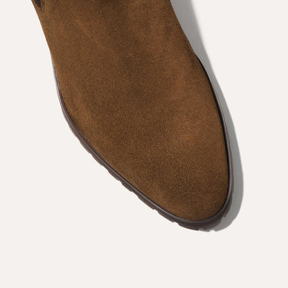 Close-up of the toe area of The Chelsea Boot - Moss Suede by Margaux, featuring brown suede and a dark brown rubber sole, shown on a white background.